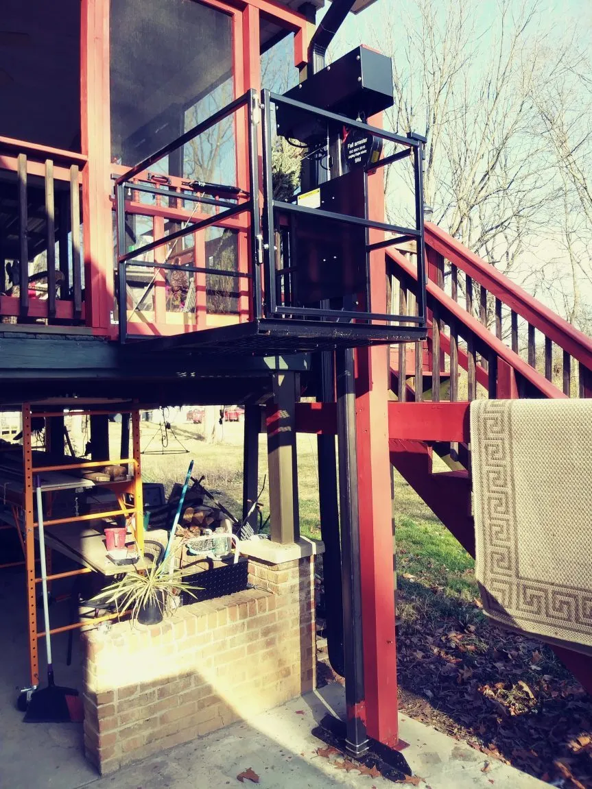 Outdoor platform lift beside a porch and railing