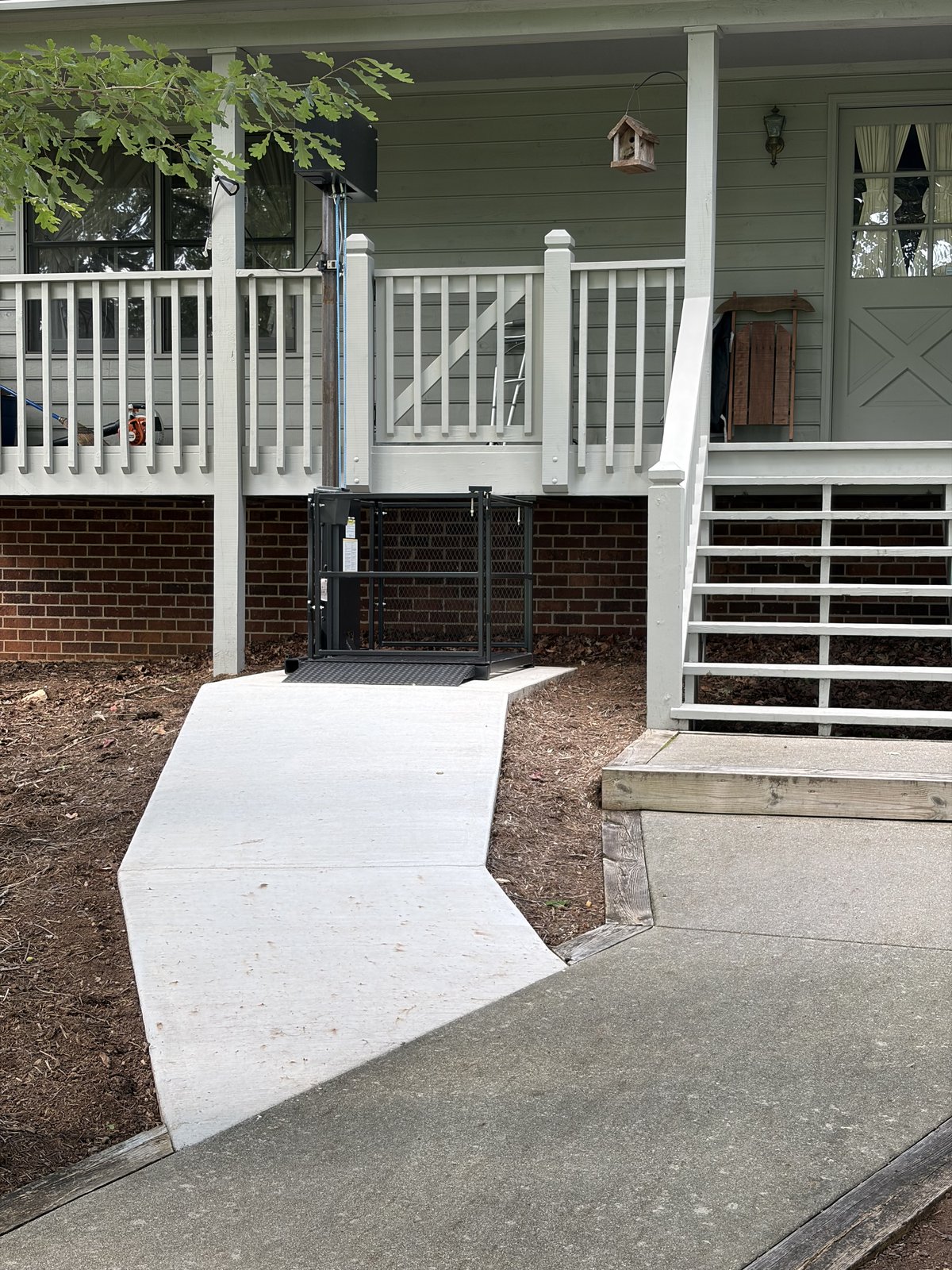 Affordable Lifts residential platform lift beside a front porch, with the platform, column, and landing gate visible